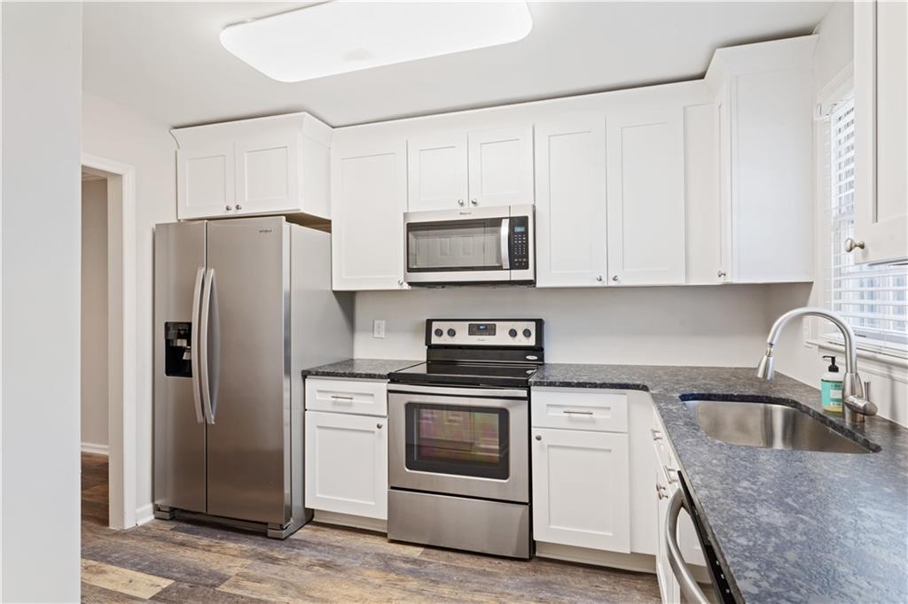 6700 Roswell Road, Unit 23A Atlanta, GA 30328 - Photo 4 of 18 a kitchen with stainless steel appliances granite countertop a refrigerator stove and sink with wooden floor