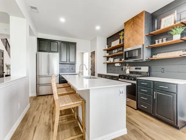 a kitchen with stainless steel appliances granite countertop a refrigerator a stove and a sink