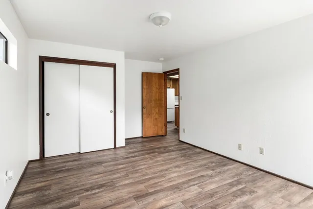 a view of an empty room with wooden floor and closet