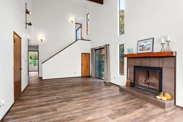 a view of an empty room with wooden floor fireplace and a window
