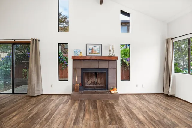 a view of an empty room with wooden floor fireplace and a window