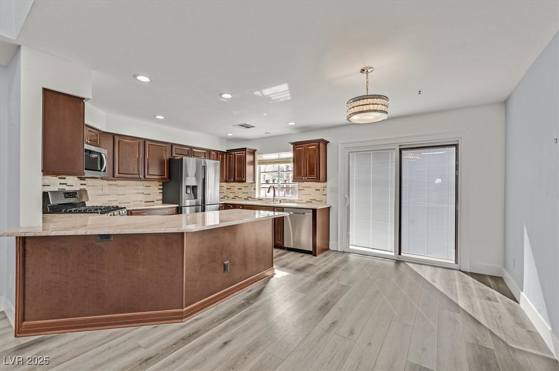 5421 Painted Mirage Road Las Vegas, NV 89149 - Photo 8 of 35 Kitchen featuring pendant lighting, appliances with stainless steel finishes, a sink, light wood-type flooring, and a peninsula