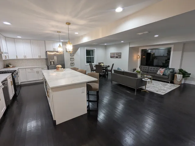 a living room with couches and kitchen view with wooden floor