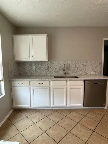 a kitchen with granite countertop white cabinets and stainless steel appliances