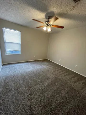 an empty room with a window and a fan
