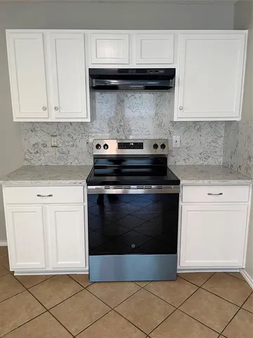 a kitchen with granite countertop white cabinets and stainless steel appliances