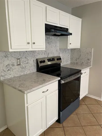 a kitchen with granite countertop white cabinets and a stainless steel appliances
