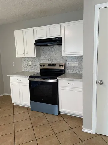 a kitchen with a stove top oven and cabinets