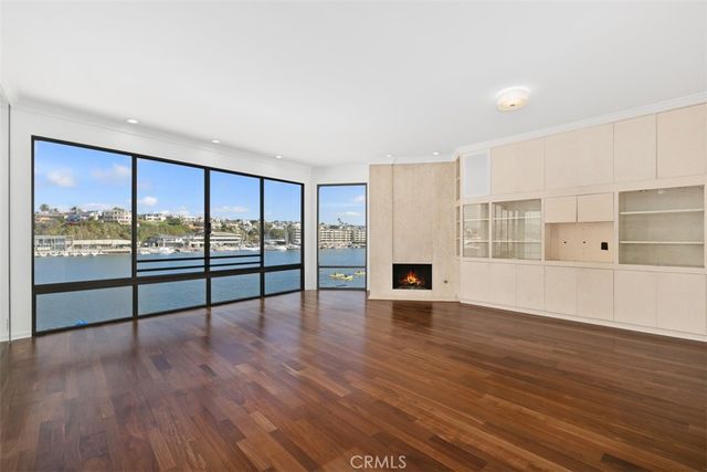 a view of an empty room with wooden floor and a fireplace