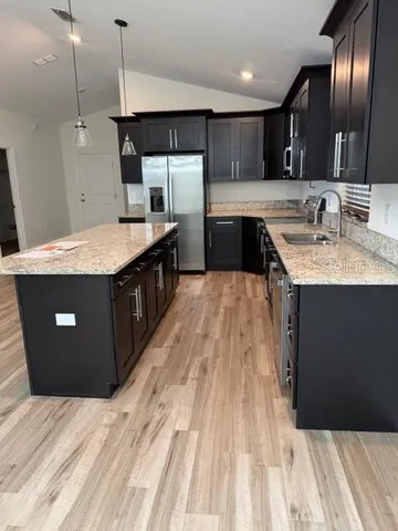 a kitchen with stainless steel appliances granite countertop a sink a stove and a wooden floors