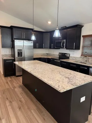 a kitchen with stainless steel appliances granite countertop a sink a stove top oven a counter space and cabinets