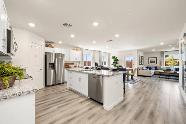 a kitchen with stainless steel appliances granite countertop a refrigerator oven a sink dishwasher and a refrigerator with wooden floor