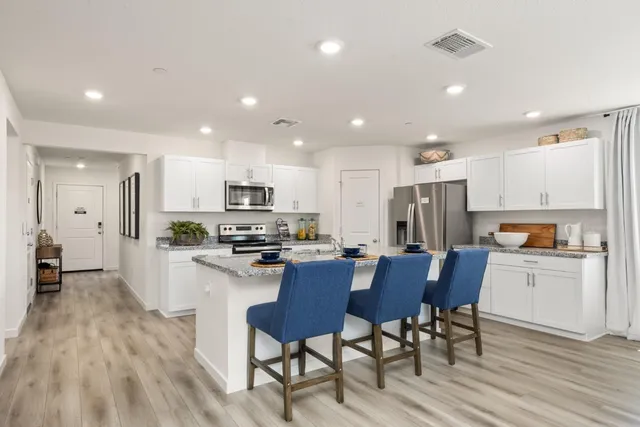 a kitchen with a refrigerator a stove top oven a sink dishwasher with a dining table and chairs