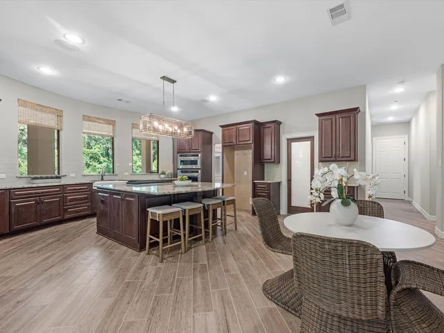 a kitchen with a dining table chairs wooden floor and appliances