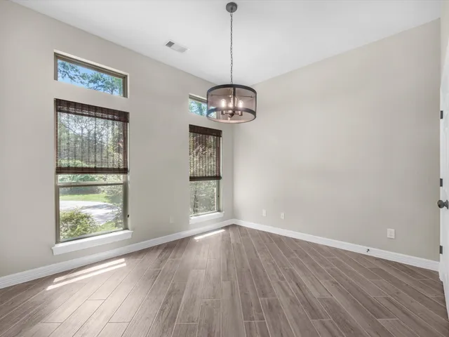 a view of a room with wooden floor chandelier and windows