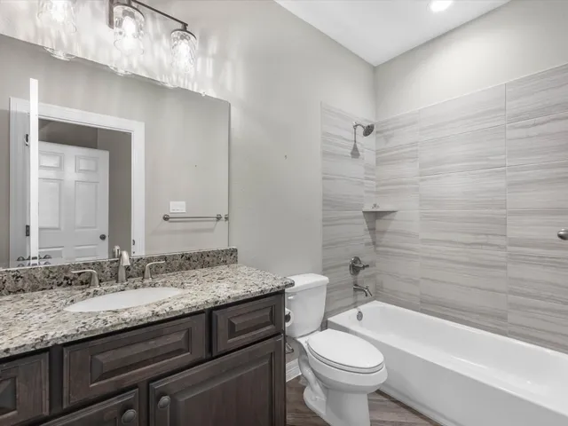 a bathroom with a granite countertop toilet a sink and a bathtub
