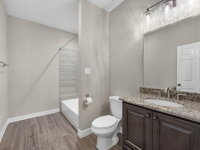 a bathroom with a granite countertop toilet sink and mirror