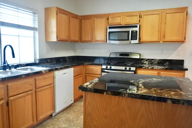 a kitchen with stainless steel appliances granite countertop a stove a sink and a microwave
