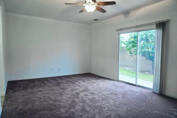 an empty room with a ceiling fan and a large window