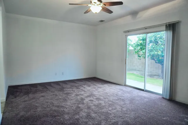 an empty room with a ceiling fan and a large window