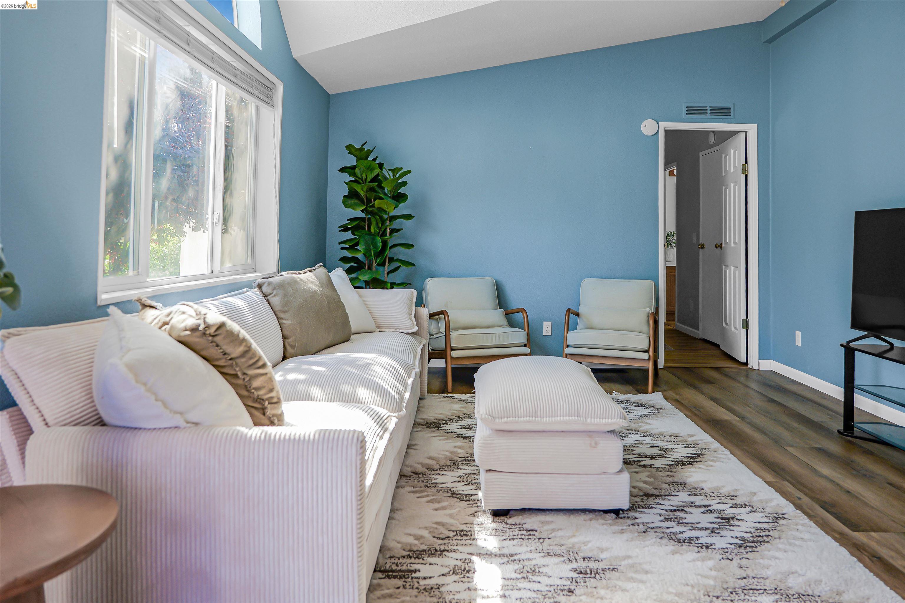 4419 Little John Road Copperopolis, CA 95228 - Photo 18 of 43 Spacious living area featuring vaulted ceilings, ample natural light from large windows, wood-finish flooring, and a light-toned area rug