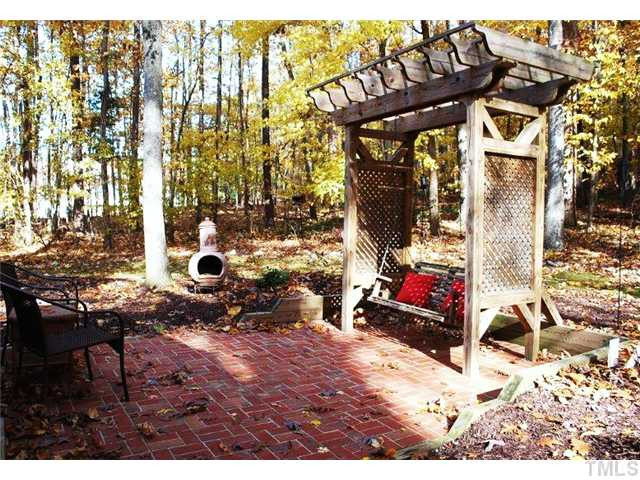 12325 Whartons Way Raleigh, NC 27613 - Photo 12 of 25 Brick patio and pergula with swing showcase the peace and seclusion of the wooded lot. Patio/Deck