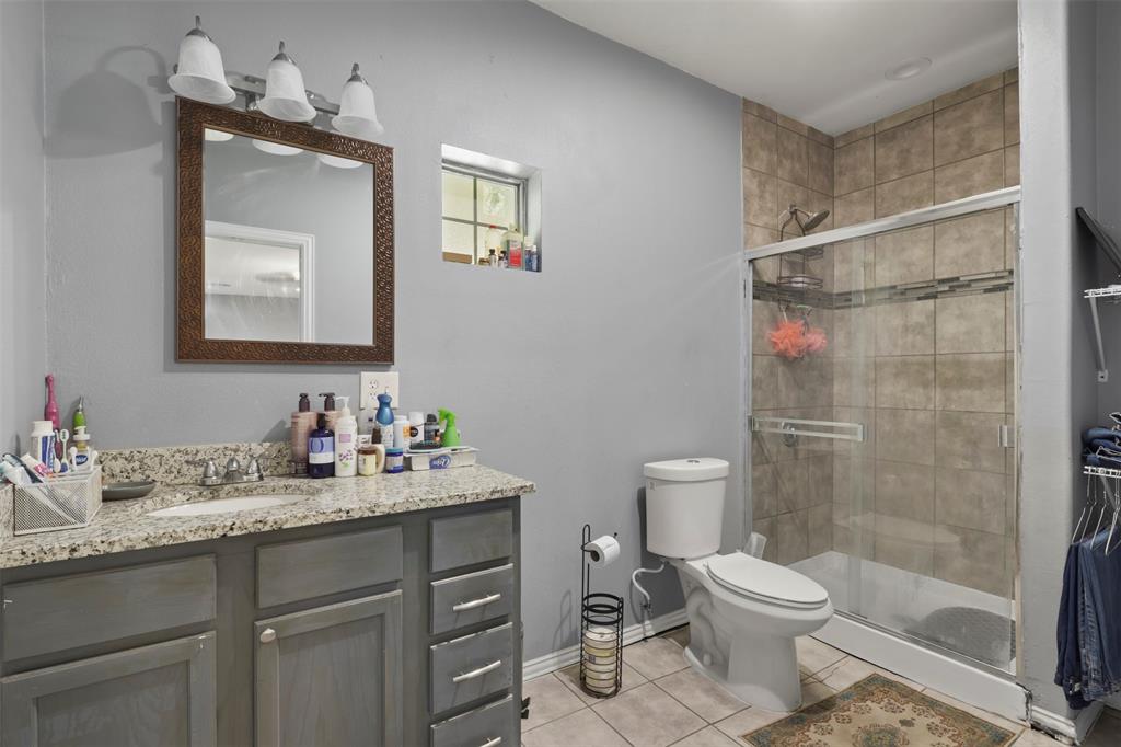 1556 John Wayne Road Kaufman, TX 75142 - Photo 11 of 33 a bathroom with a toilet sink vanity and mirror