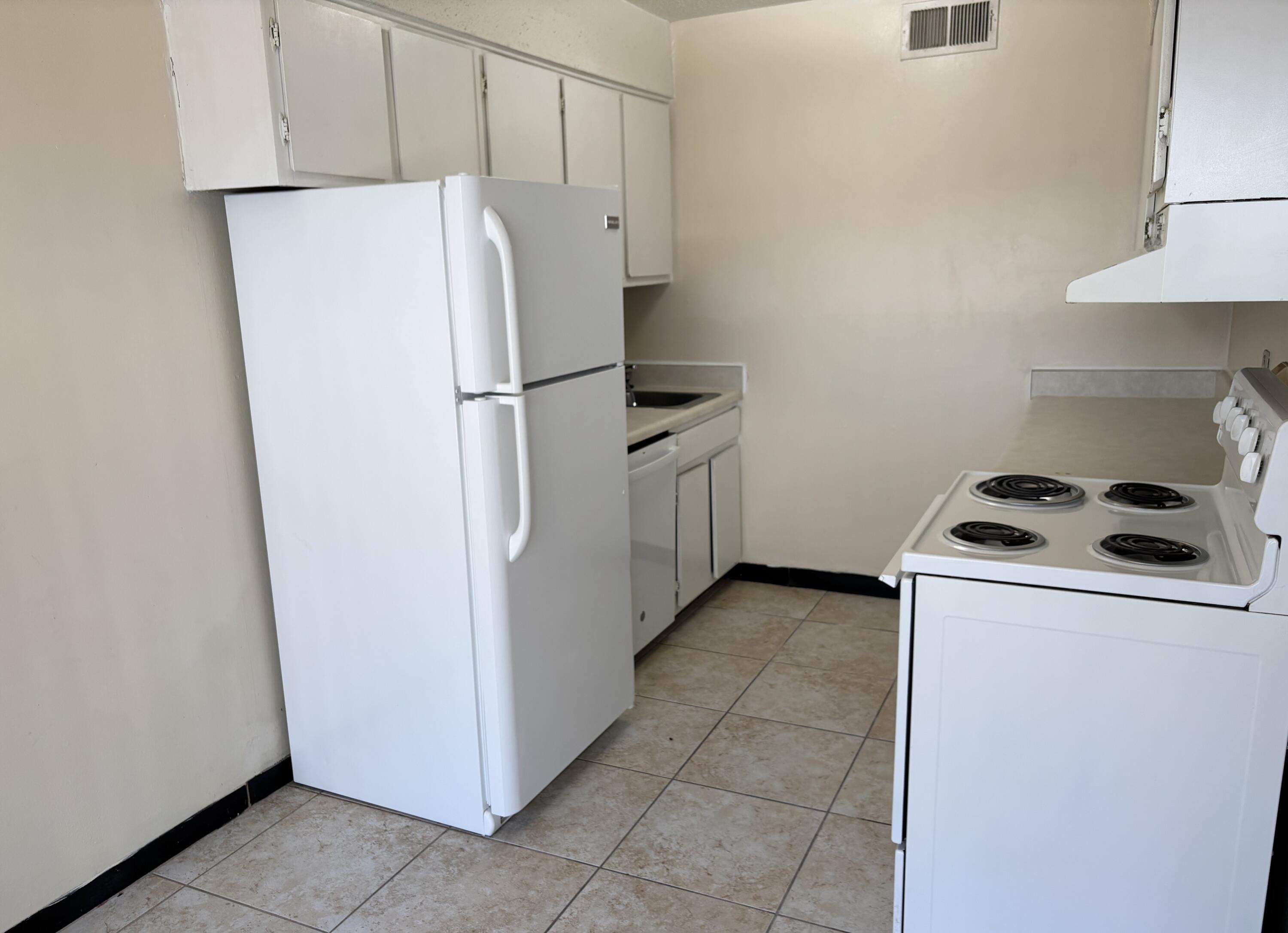 210 Pelham Road, Unit 101B Fort Walton Beach, FL 32547 - Photo 6 of 10 a white refrigerator freezer and a stove sitting inside of a kitchen