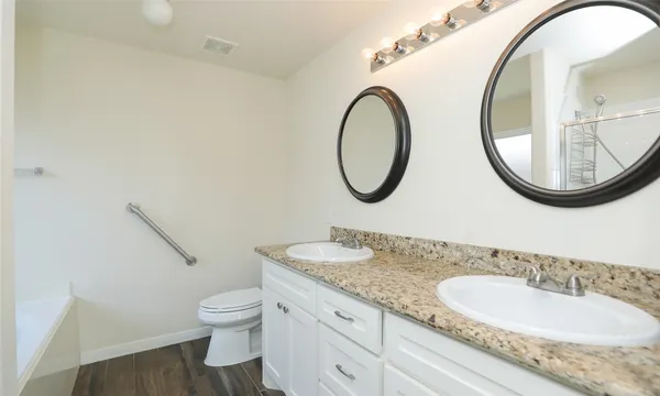 a bathroom with a granite countertop toilet a sink and a mirror