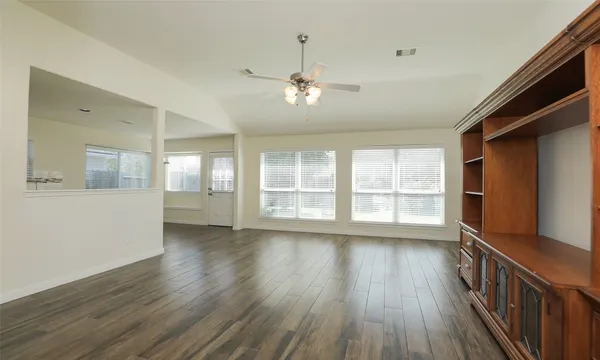 a view of an empty room with wooden floor and a window