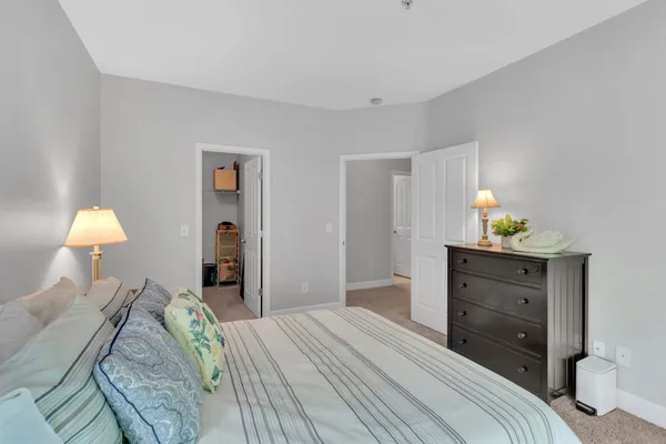 a bedroom with a bed and a lamp on dresser