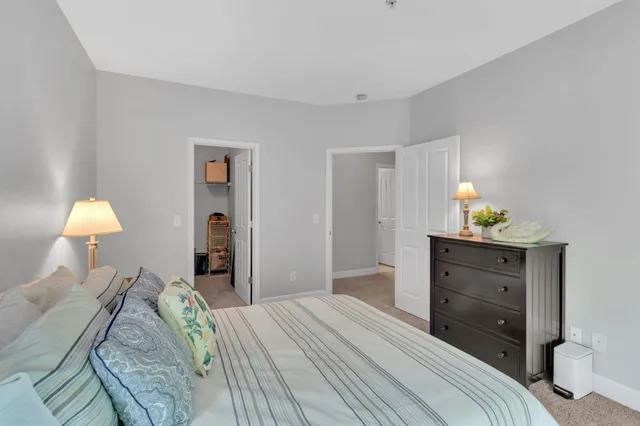 a bedroom with a bed and a lamp on dresser