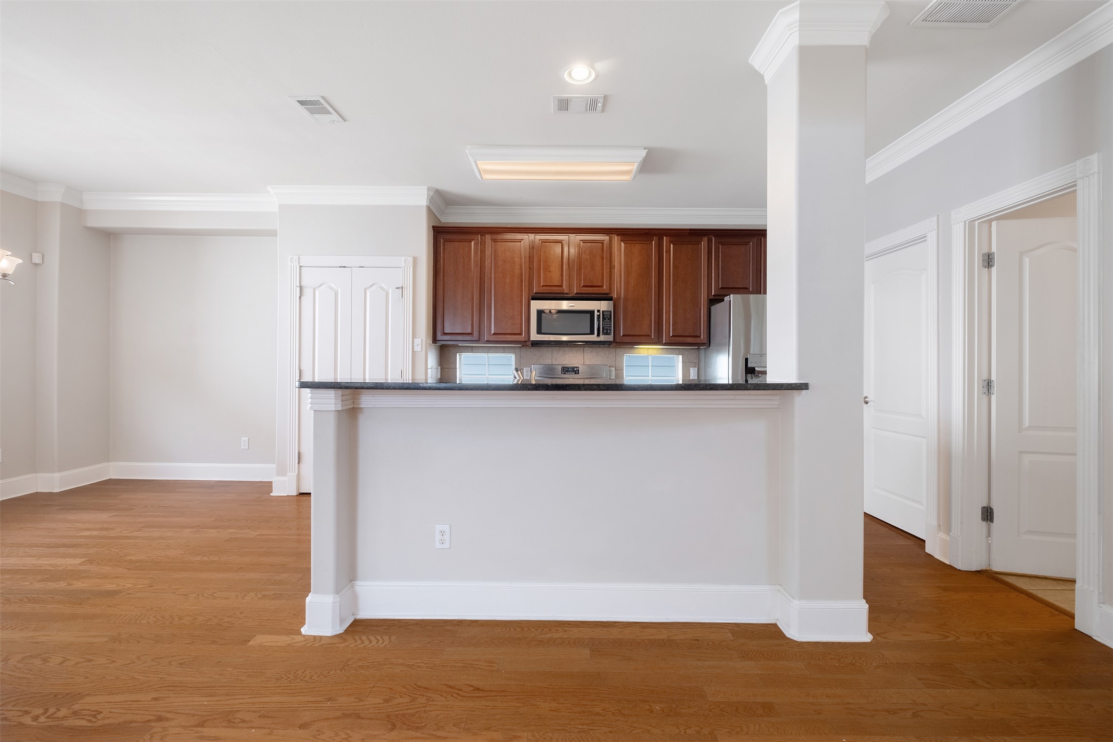 6715 Windrift Way, Unit 8 Austin, TX 78745 - Photo 10 of 24 A streamlined kitchen flows into an airy living area, featuring rich hardwood floors and elegant crown molding.