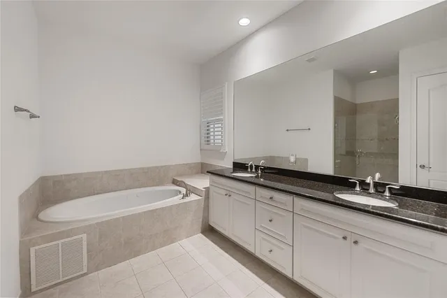 a bathroom with a granite countertop bathtub sink and mirror