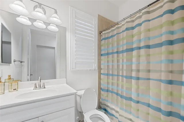 a bathroom with a sink a toilet a mirror and shower curtain