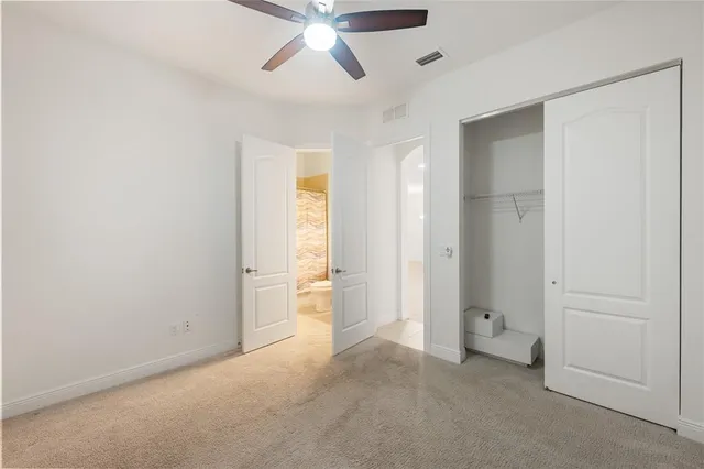 a view of an empty room and chandelier fan