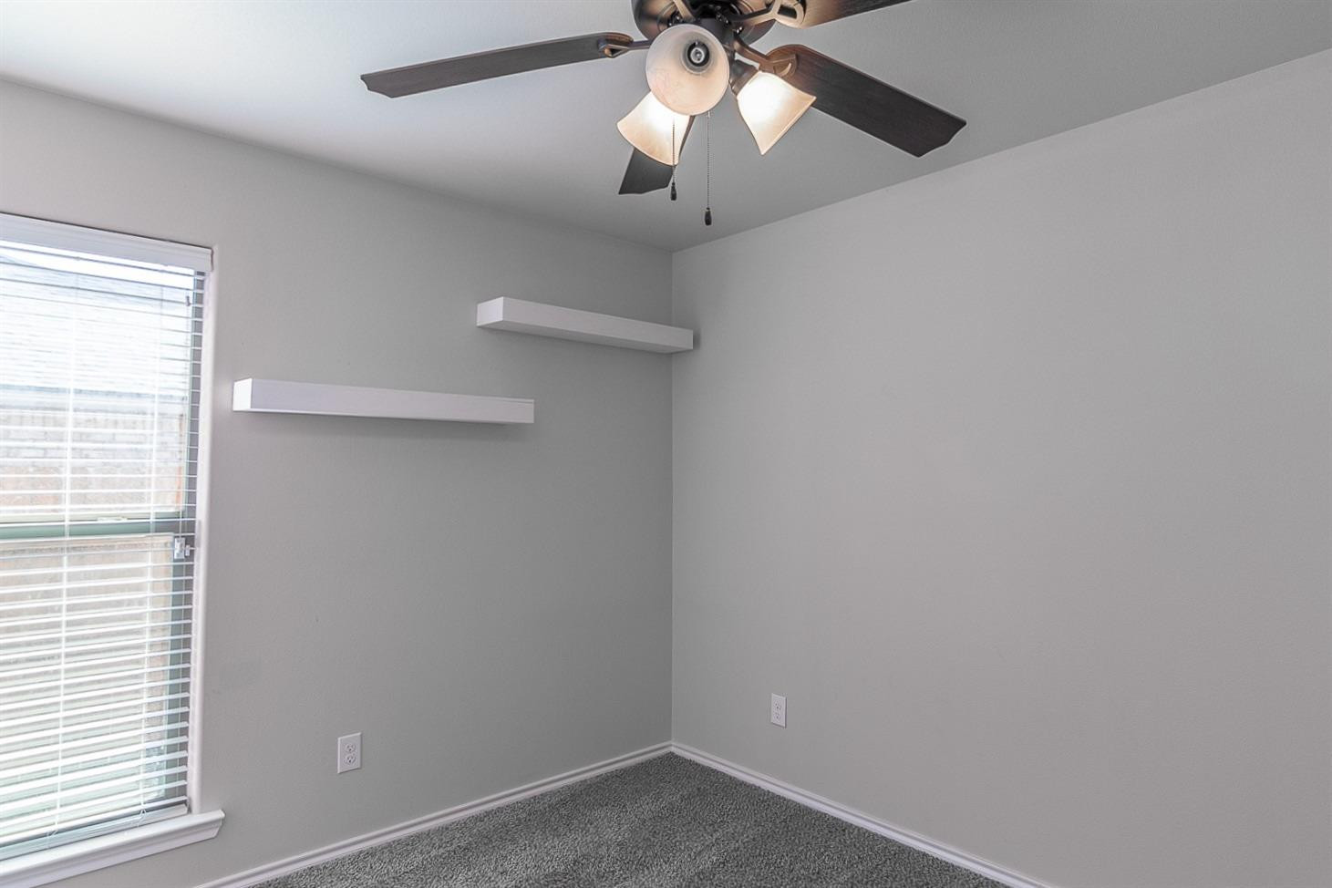 7449 104th Street Lubbock, TX 79424 - Photo 11 of 16 an empty room with a window and a fan