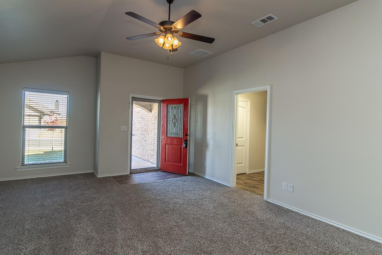 7449 104th Street Lubbock, TX 79424 - Photo 2 of 16 an empty room with windows and chandelier fan