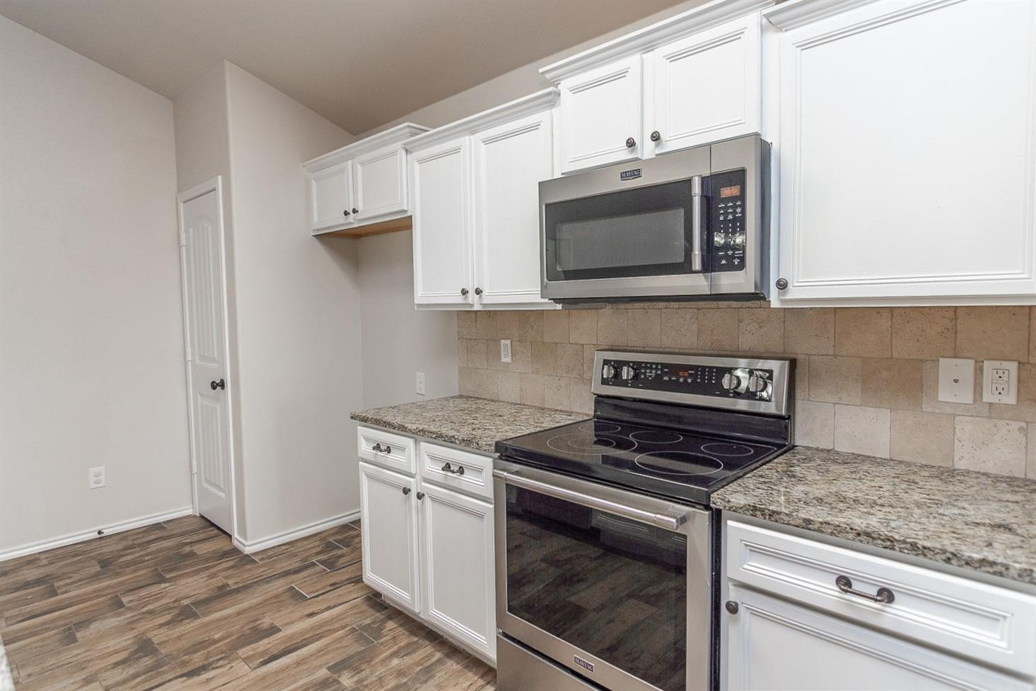 7449 104th Street Lubbock, TX 79424 - Photo 6 of 16 a kitchen with granite countertop a stove and a microwave