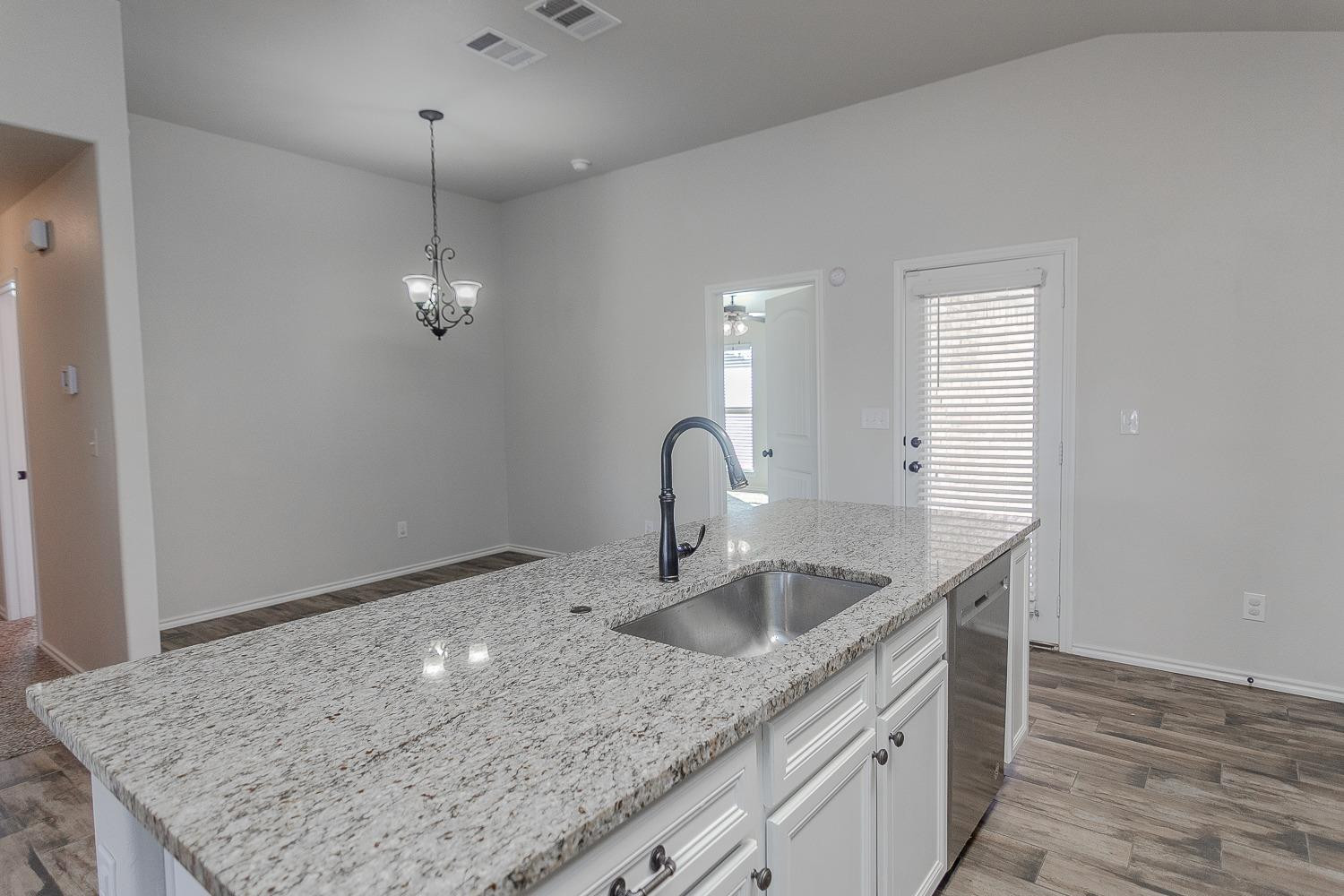 7449 104th Street Lubbock, TX 79424 - Photo 7 of 16 a kitchen with granite countertop a sink a counter space and cabinets
