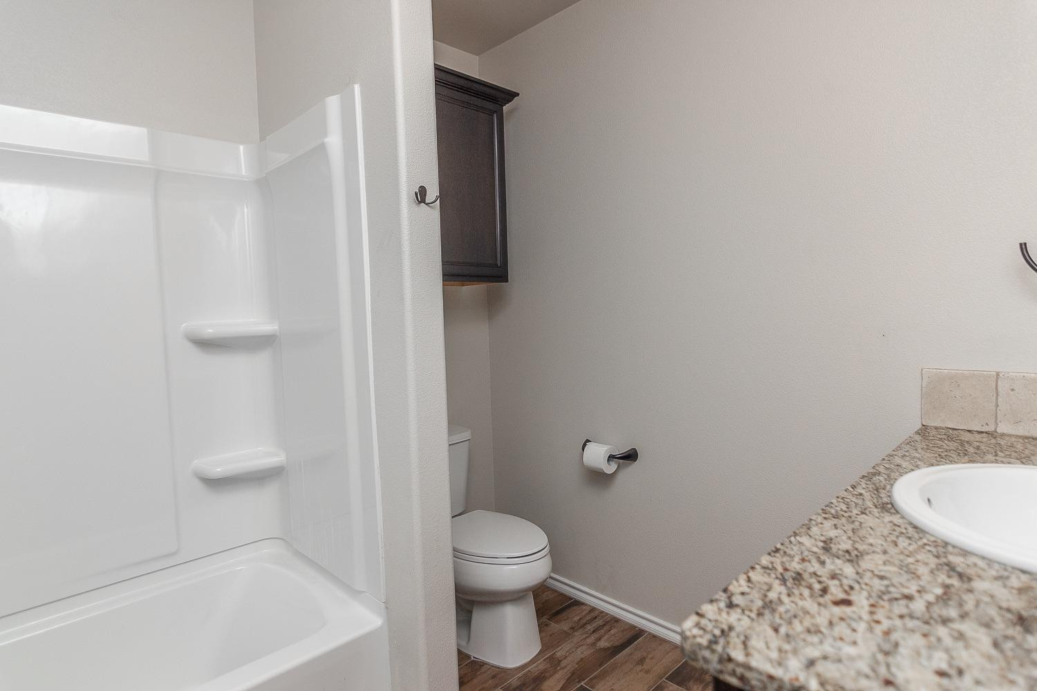 7449 104th Street Lubbock, TX 79424 - Photo 10 of 16 a bathroom with a granite countertop sink a toilet and shower