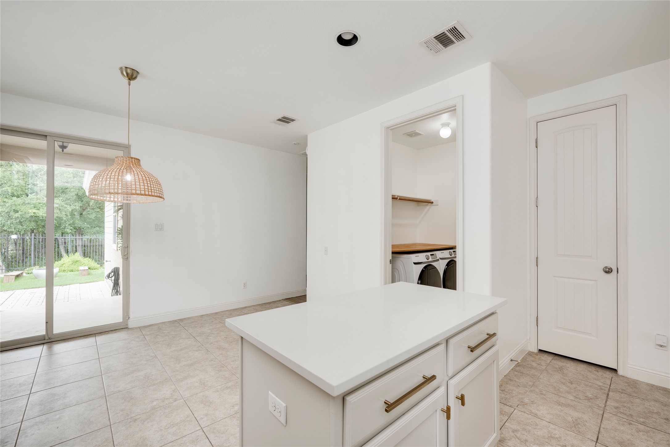 6008 Whipple Way Austin, TX 78745 - Photo 16 of 39 A laundry alcove featuring a washer and dryer stands adjacent to an island, all set against neutral-toned tile flooring.