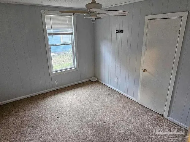 an empty room with windows and fan
