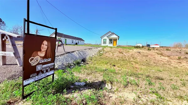 a front view of a house with a yard and sign board