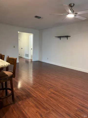 an empty room with wooden floor a ceiling fan and windows