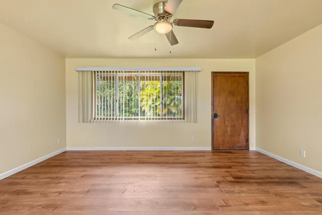 a view of an empty room with window and wooden floor