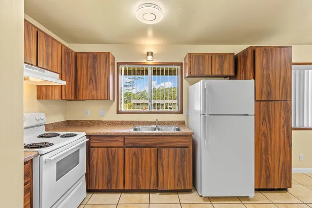 a kitchen with stainless steel appliances granite countertop a refrigerator a sink a stove and a refrigerator