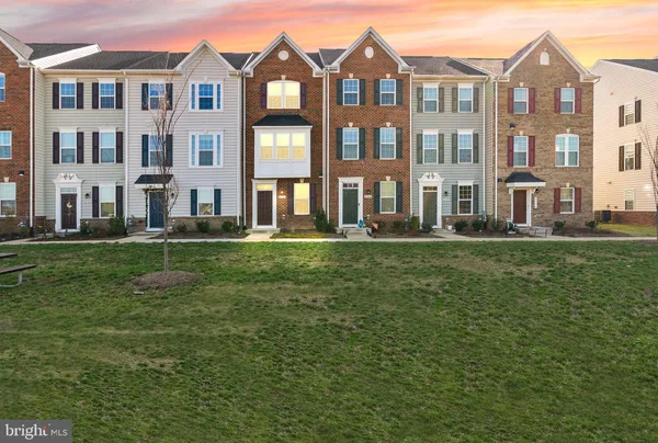 a front view of a building with garden and trees