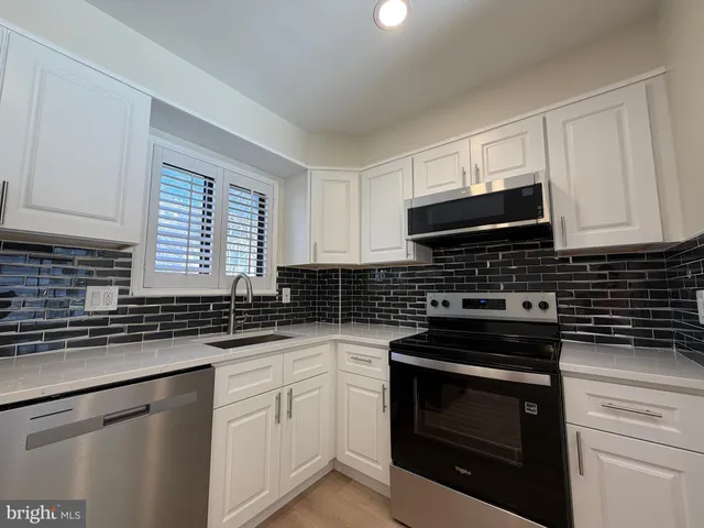 a kitchen with granite countertop a sink stove and microwave
