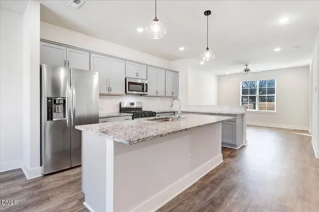 a large kitchen with kitchen island a large counter top space a sink stainless steel appliances and cabinets